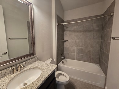 Full bath with shower / washtub combination, a textured wall, vanity, and dark tile patterned floors
