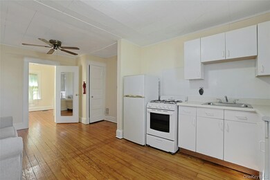 Kitchen featuring white cabinets, white appliances, light countertops, light wood-style floors, and ornamental molding