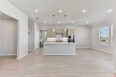 Kitchen featuring recessed lighting, a kitchen island with sink, light wood-type flooring, hanging light fixtures, and oven