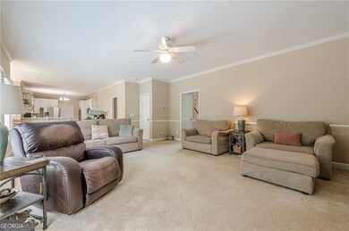 Living room with ornamental molding, light carpet, ceiling fan, and baseboards