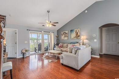 Living room with ceiling fan, wood finished floors, baseboards, and high vaulted ceiling