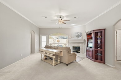 The spacious family room features cozy, neutral-toned carpet, and a cozy fireplace centerpiece. Arched doorways lead to other areas of the home, creating an inviting flow.