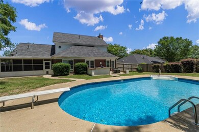 View of swimming pool featuring a diving board, a sunroom, and a patio area