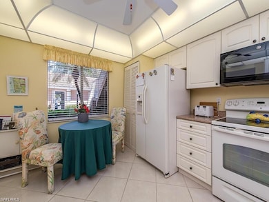 Kitchen featuring white appliances, white cabinetry, light tile patterned flooring, and a ceiling fan