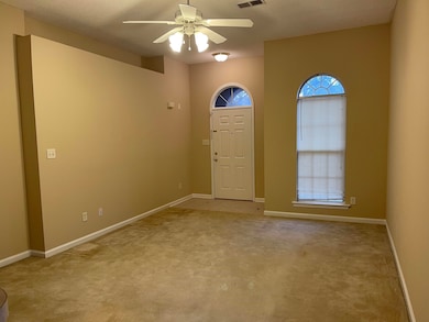 Entrance foyer with ceiling fan and light carpet