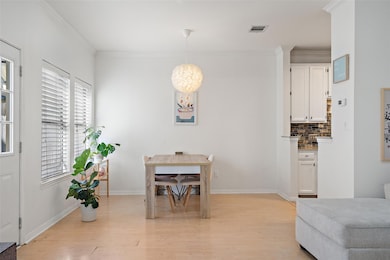 Dining space featuring light wood-style floors, healthy amount of natural light, and ornamental molding