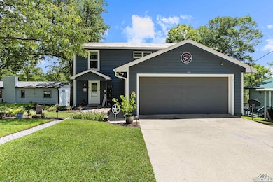View of front of home with concrete driveway, a front lawn, a metal roof, and an attached garage