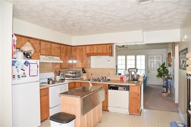 Kitchen with a sink, white appliances, under cabin