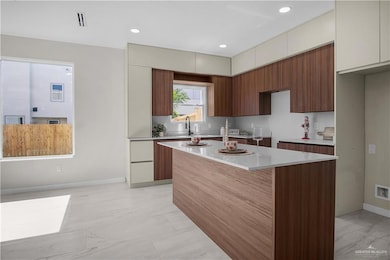 Kitchen featuring modern cabinets, brown cabinets, light stone countertops, a center island, and recessed lighting