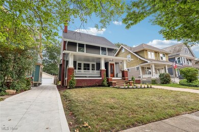 View of front of house featuring a porch, a garage, an outbuilding, and a front yard
