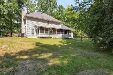 Back of house featuring a chimney, a sunroom, and a lawn