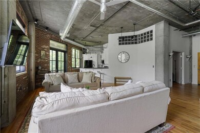 Living area featuring brick wall, wood finished floors, and a towering ceiling