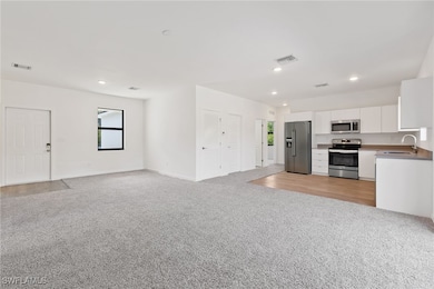 Kitchen with a sink, white cabinets, visible vents