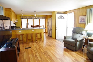 Kitchen featuring a breakfast bar area, pendant lighting, stainless steel refrigerator, sink, and kitchen peninsula