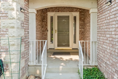 View of Front exterior entry featuring brick siding, spacious front porch and railings