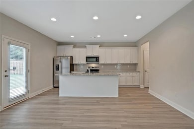 Kitchen with white cabinetry, an island with sink,