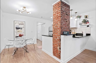Kitchen featuring dark countertops, freestanding refrigerator, light wood-style flooring, a chandelier, and white cabinetry