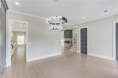 Unfurnished dining area featuring crown molding, recessed lighting, light wood-style floors, stairs, and a chandelier
