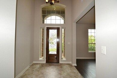 Elegant entry with a beveled glass front door with wrought iron rail accents, two story high ceilings and tile floors.