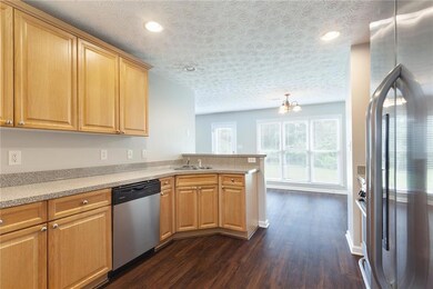 Kitchen featuring appliances with stainless steel finishes, dark wood-style floors, a peninsula, a chandelier, and recessed lighting