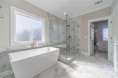 Primary Bathroom featuring crown molding, plenty of natural light, and separate shower and tub