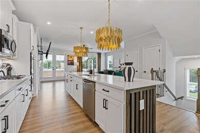 Kitchen with a sink, appliances with stainless steel finishes, french doors, a chandelier, and light wood-style flooring