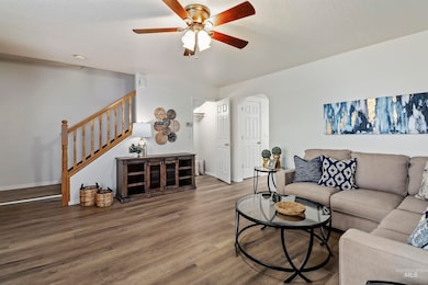 Living area with wood finished floors, stairway, ceiling fan, and arched walkways