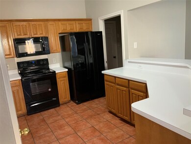 Kitchen with black appliances, light tile patterned floors, and brown cabinets