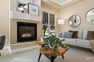 Living area with a glass covered fireplace, crown molding, a ceiling fan, and tile patterned flooring