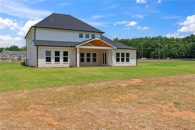 Rear view of property with a lawn, roof with shingles, and brick siding