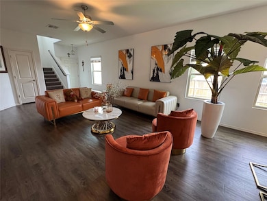 Living room with wood finished floors, stairs, and a ceiling fan