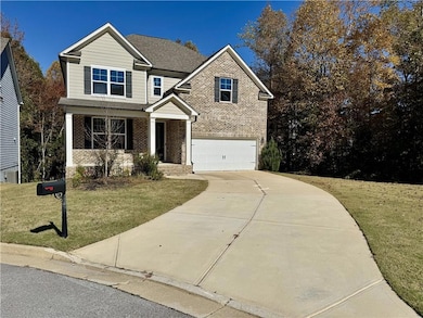 View of front facade with brick siding, covered porch, a front yard, and driveway