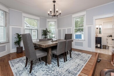 Enormous dining room with gleaming hardwood, moldings and huge style bay window setting.  Note the gorgeous powder room through the doorway...