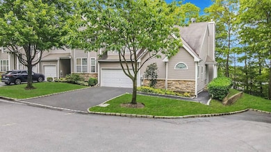 View of front of home with stone siding, an attached garage, driveway, and a front lawn
