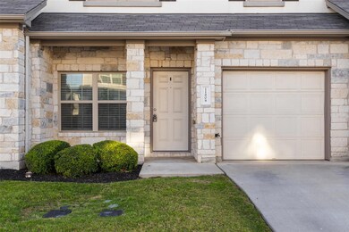 Doorway to property featuring a garage, stone siding, and concrete driveway