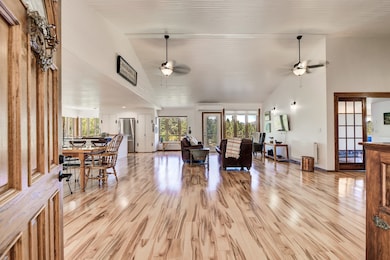 Living area with a ceiling fan, light wood-type flooring, high vaulted ceiling, and radiator