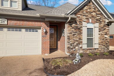 Doorway to property featuring stone siding, roof w