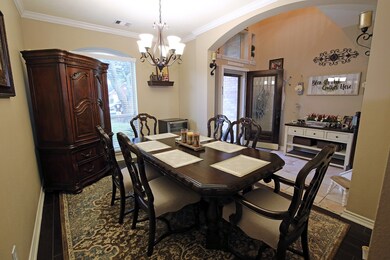 This cozy dining room is warmly lit by an elegant chandelier and natural light from a large window. 