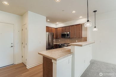 Well-appointed kitchen with stainless steel appliances, wood cabinetry, and bar seating.