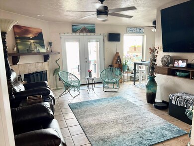 Tiled living room featuring french doors, a fireplace, a textured ceiling, and ceiling fan