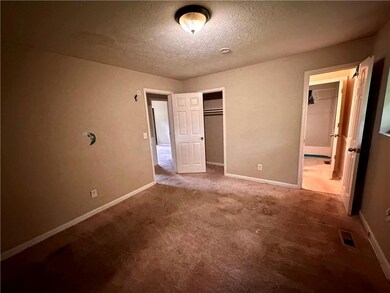 Unfurnished bedroom with carpet floors, a textured ceiling, a closet, and connected bathroom