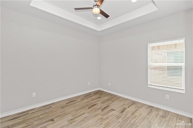 Empty room featuring baseboards, a ceiling fan, and a raised ceiling