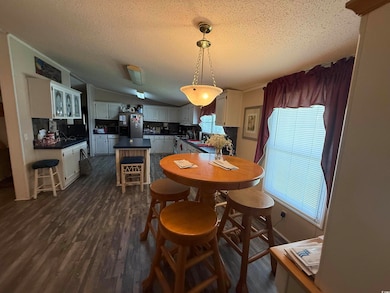 Dining area featuring a textured ceiling, dark wood finished floors, vaulted ceiling, and ornamental molding