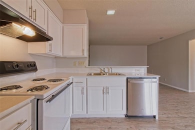 Kitchen with white electric stove, dishwasher, un
