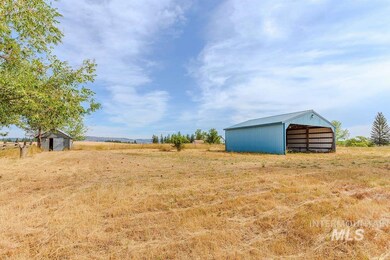 View of grassy yard with an outbuilding, a pole building, and a rural view