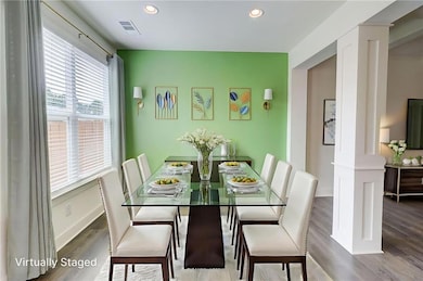 Dining room with healthy amount of natural light, wood finished floors, recessed lighting, and decorative columns