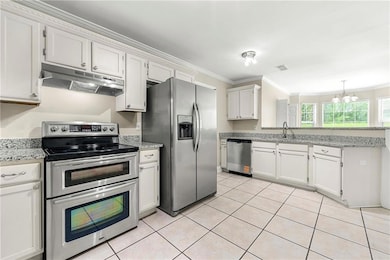 Kitchen featuring appliances with stainless steel finishes, under cabinet range hood, ornamental molding, a peninsula, and a chandelier