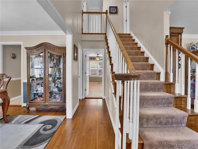 Stairway with wood-type flooring and crown molding