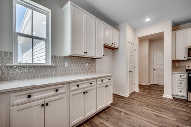 Kitchen with stainless steel appliances, decorative backsplash, white cabinets, light countertops, and recessed lighting