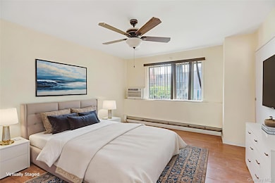 Bedroom with light wood-type flooring, a baseboard radiator, and ceiling fan